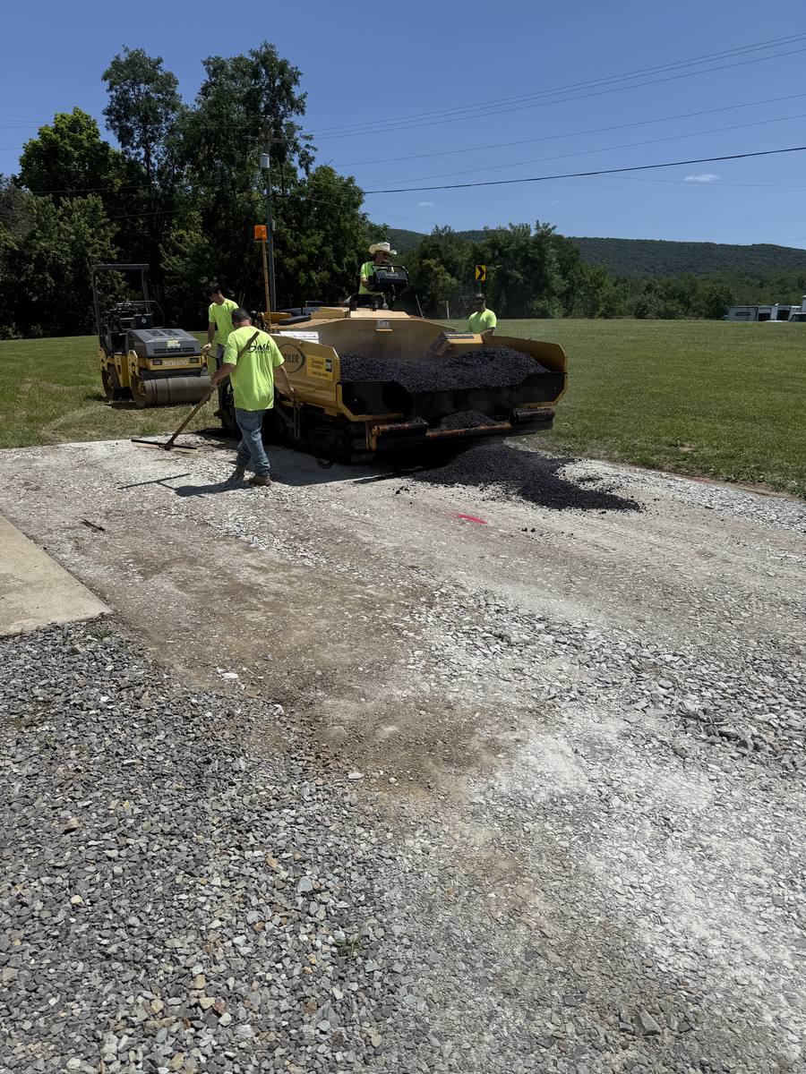 Dash Construction crew operating a paver and roller on a fresh asphalt job